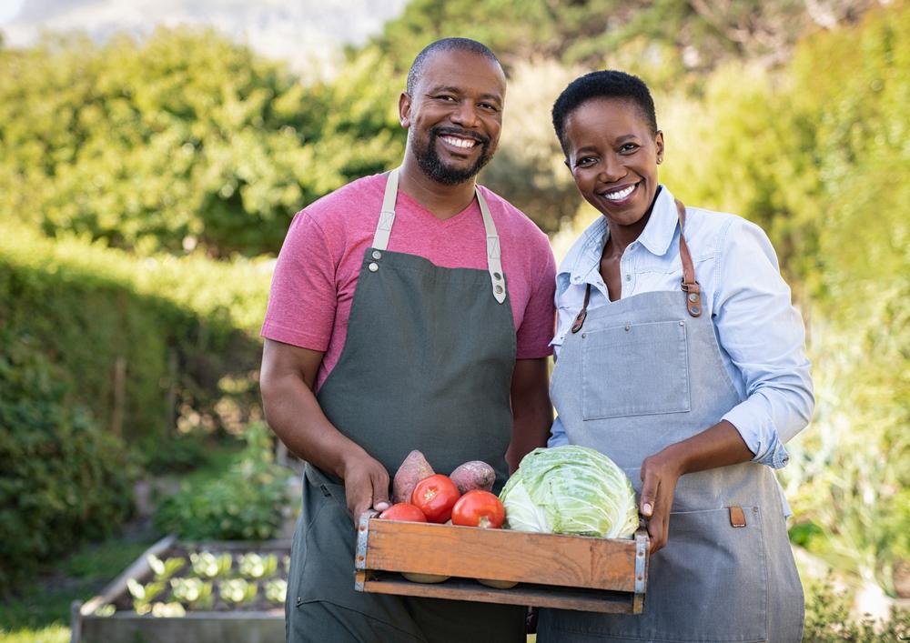 Two farmers holding a crate of fresh vegetables