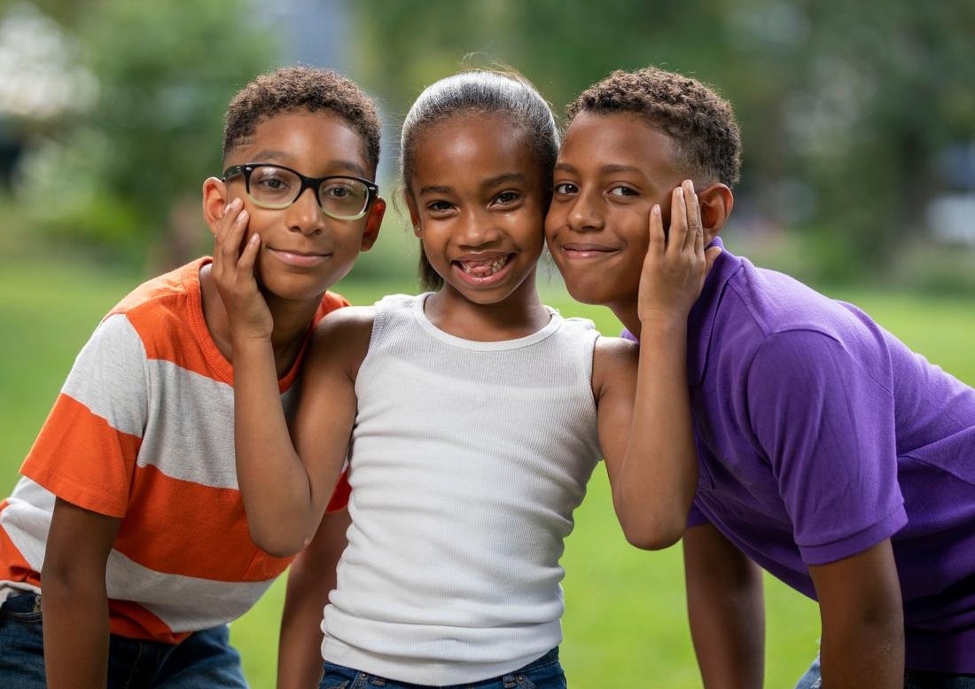Three smiling children outdoors